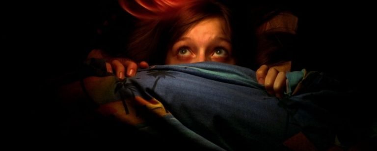 Vrouw ligt met angst onder de dekens verstopt