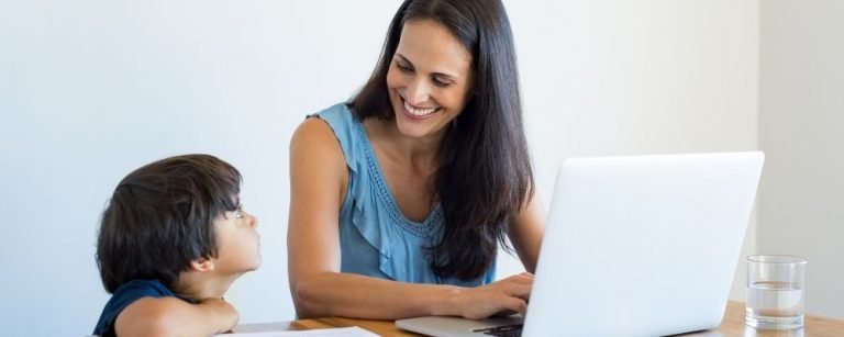 Vrouw werkend aan de laptop en kijkt lachend naar haar kind