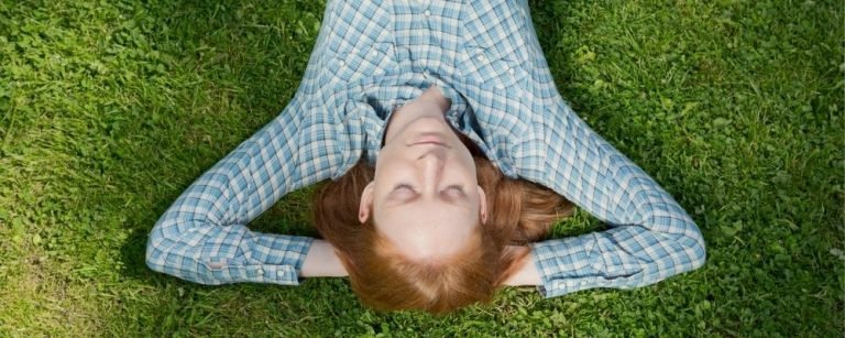 Relaxende vrouw ligt met gesloten ogen op het gras