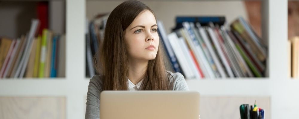 Vrouw kan zich niet concentreren en kijkt weg van haar laptop
