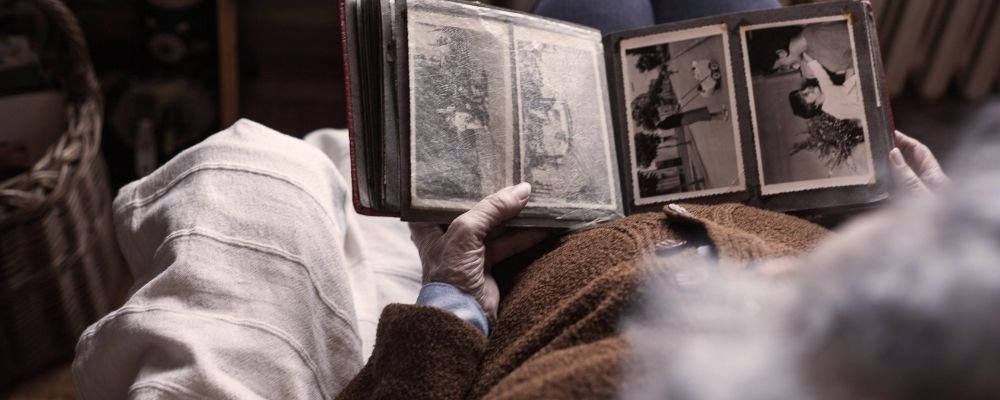 Oude vrouw kijkt naar nostalgische foto's