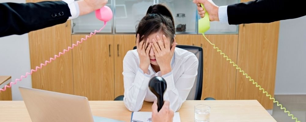 Vrouw op het werk met handen over haar ogen door stress