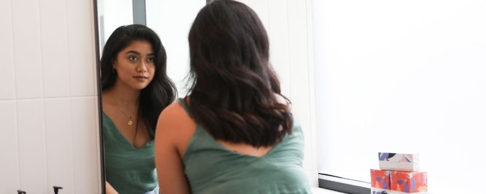 Vrouw kijkt in de spiegel en is bewust van zichzelf