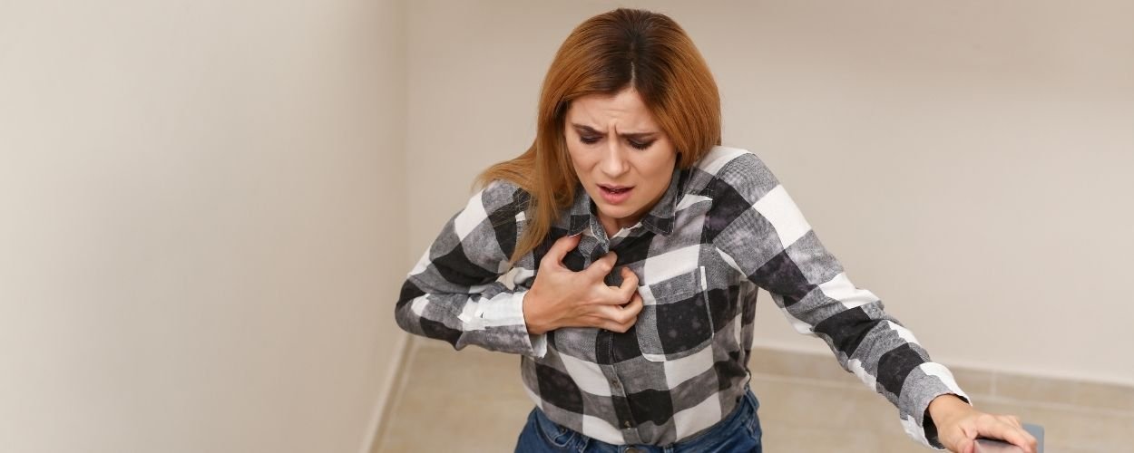 Vrouw die haar borst grijpt en moeilijk kan ademen